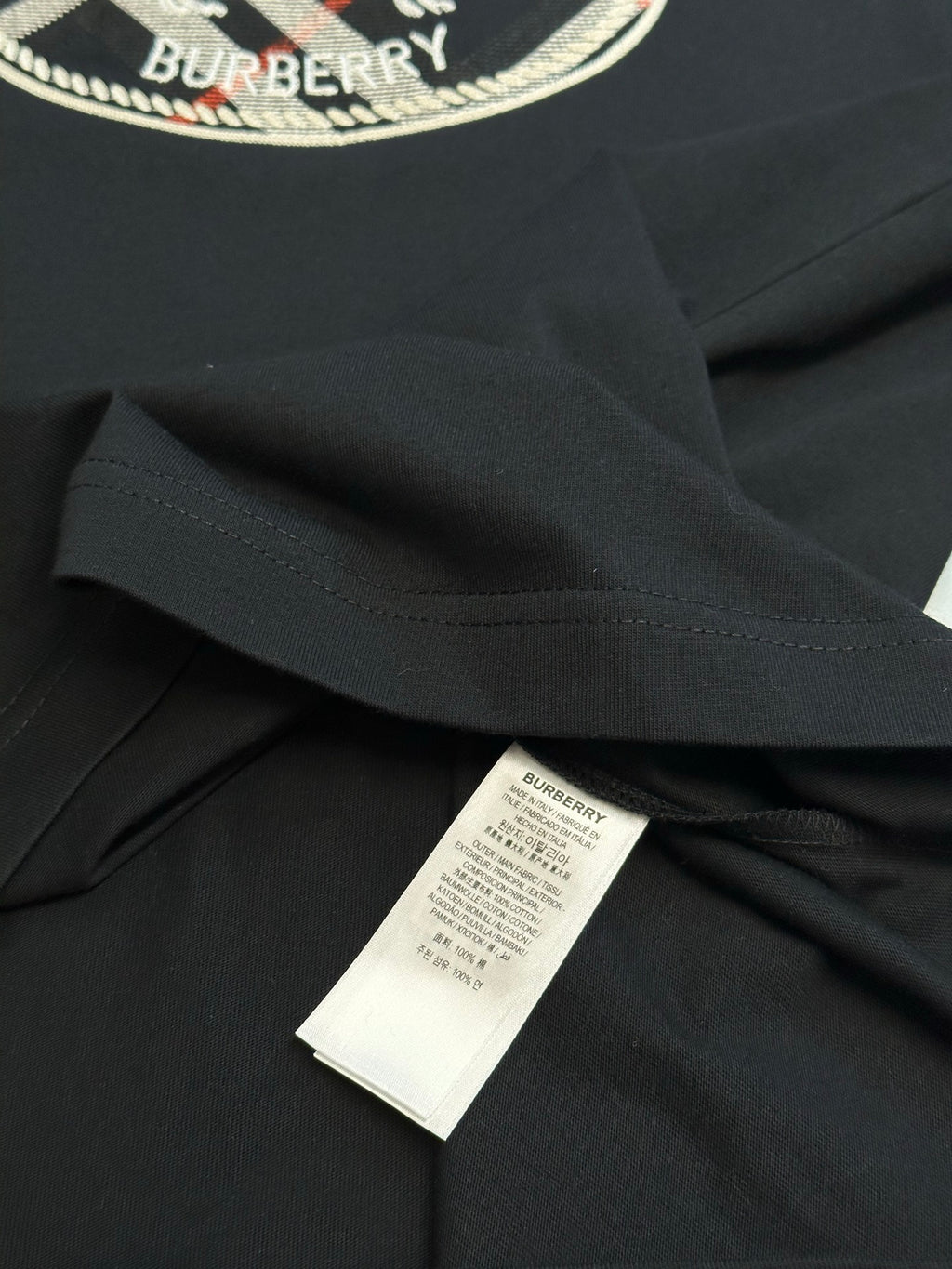 Black T-shirt fabric and hem with white size label on the inside.
