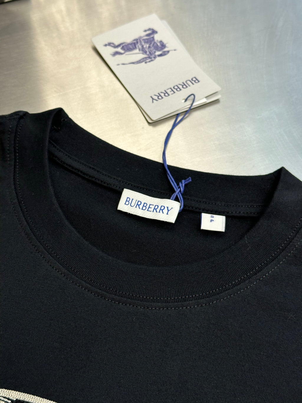 Black crew-neck T-shirt neckline with Burberry brand label and size tag.