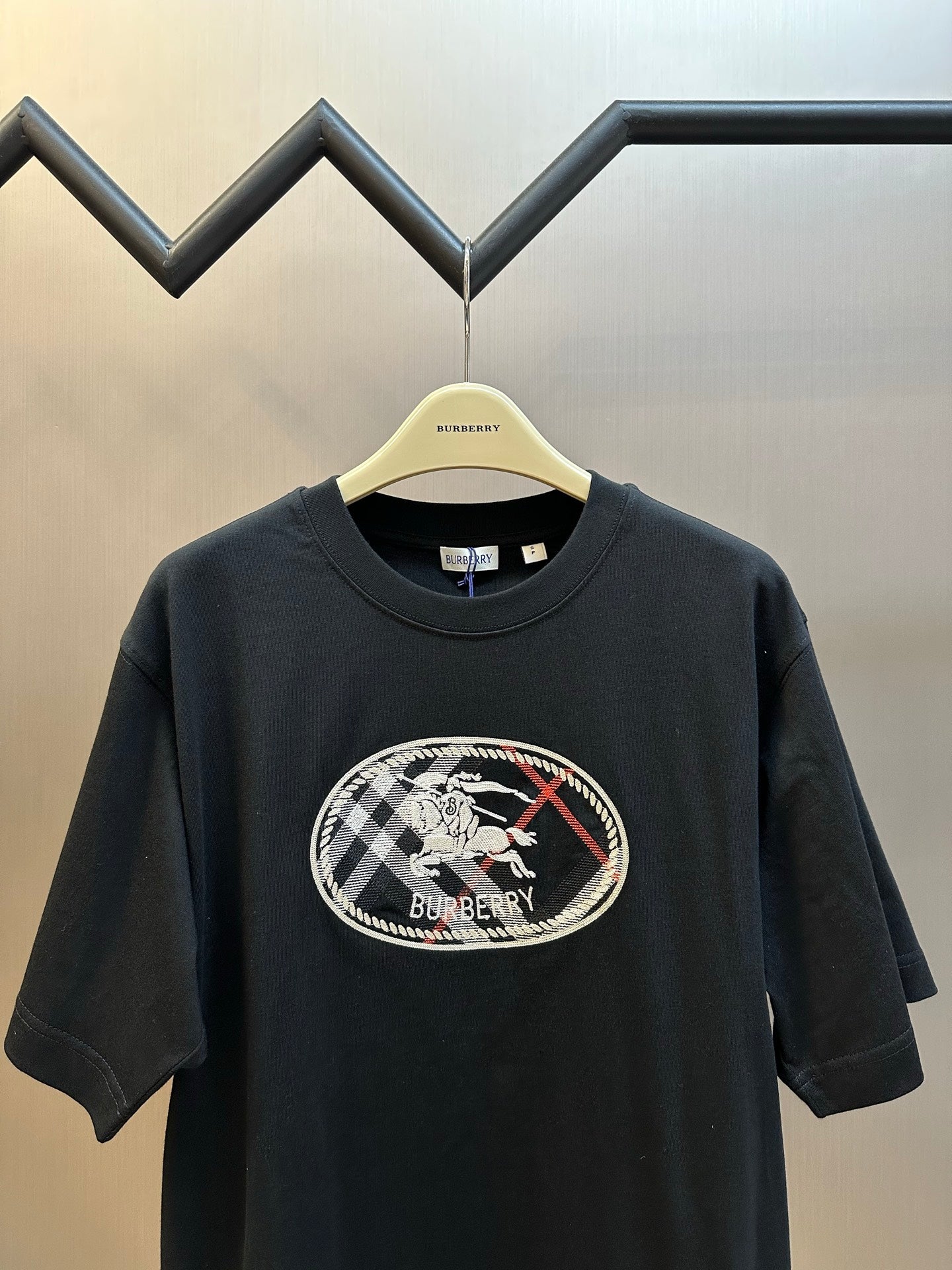 Black short-sleeve T-shirt front view with large oval Burberry logo graphic.