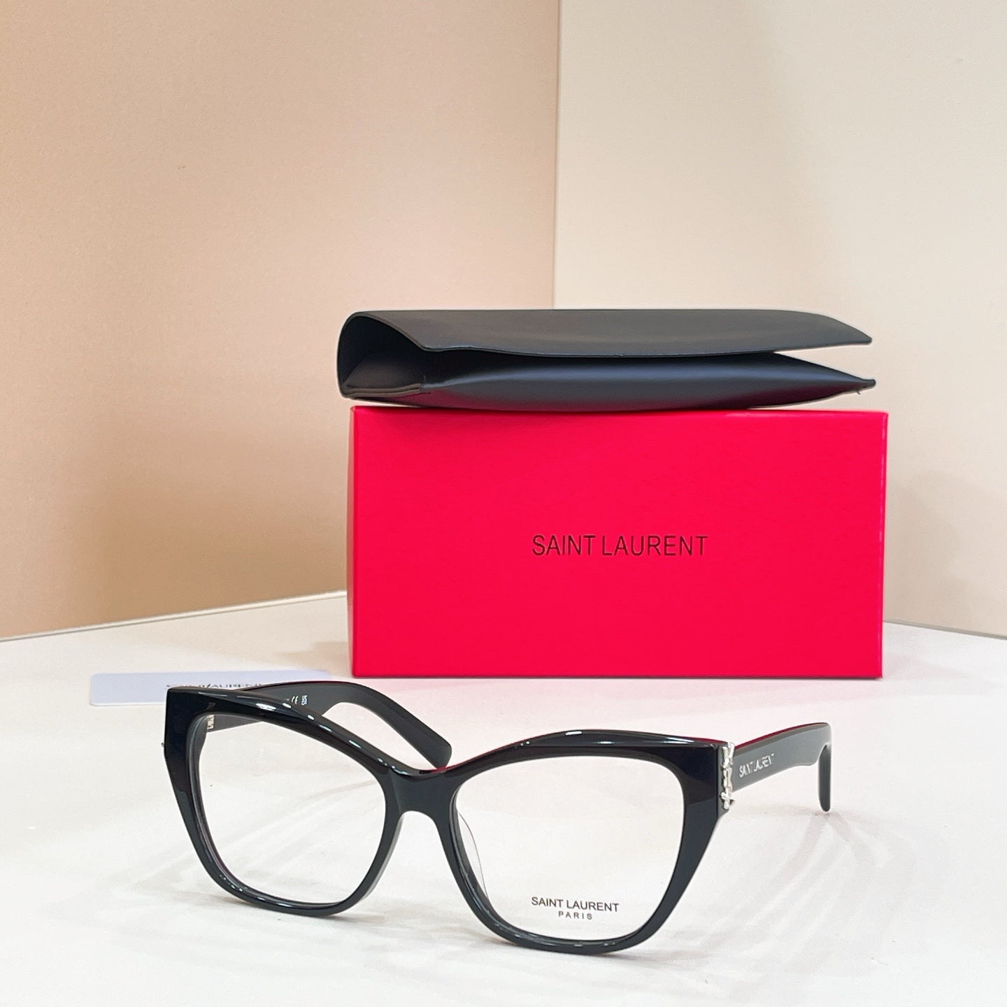 Eyeglasses with black frames, clear lenses, and gold logo detail at temple