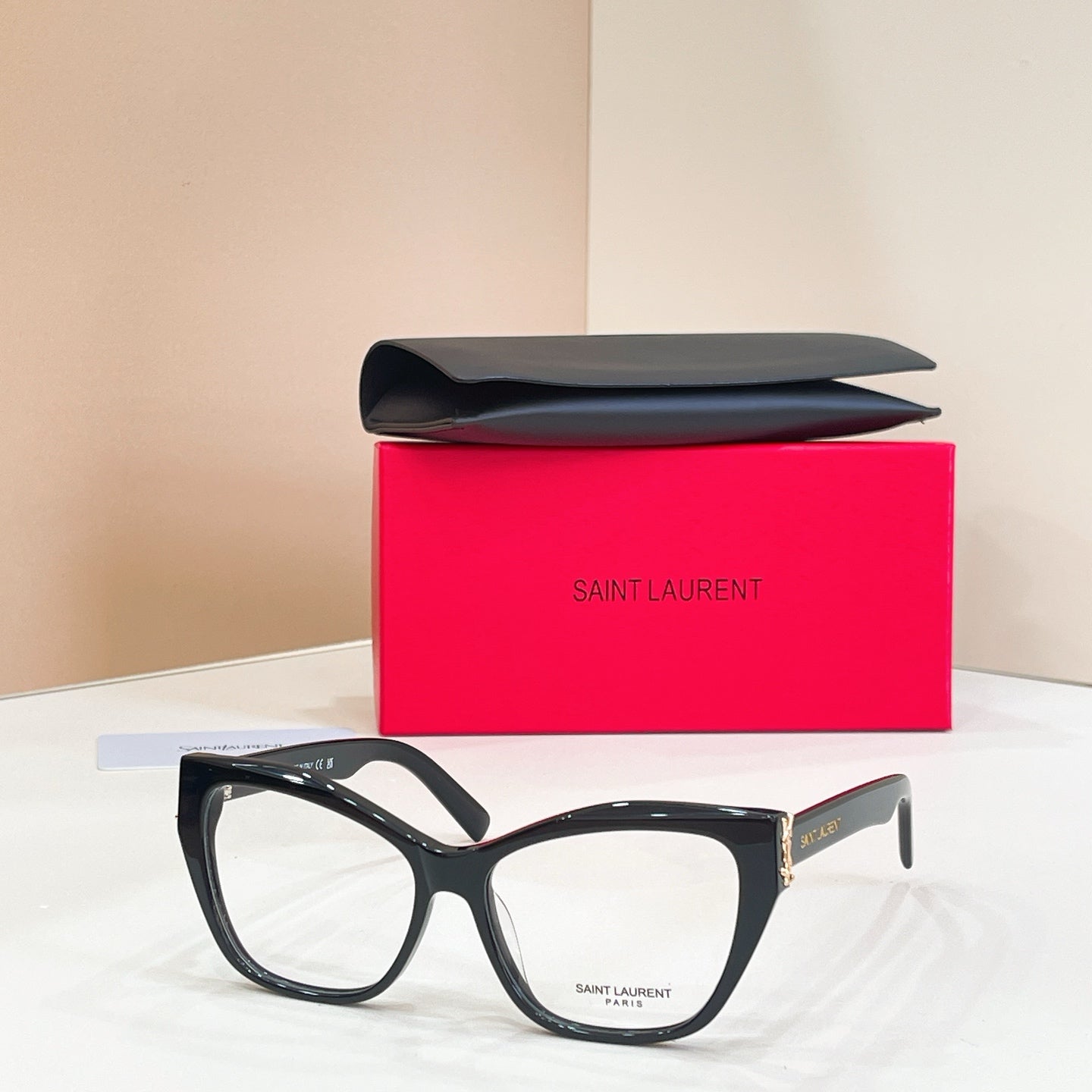 Eyeglasses with dark blue-black frames, clear lenses, and gold logo detail at temple