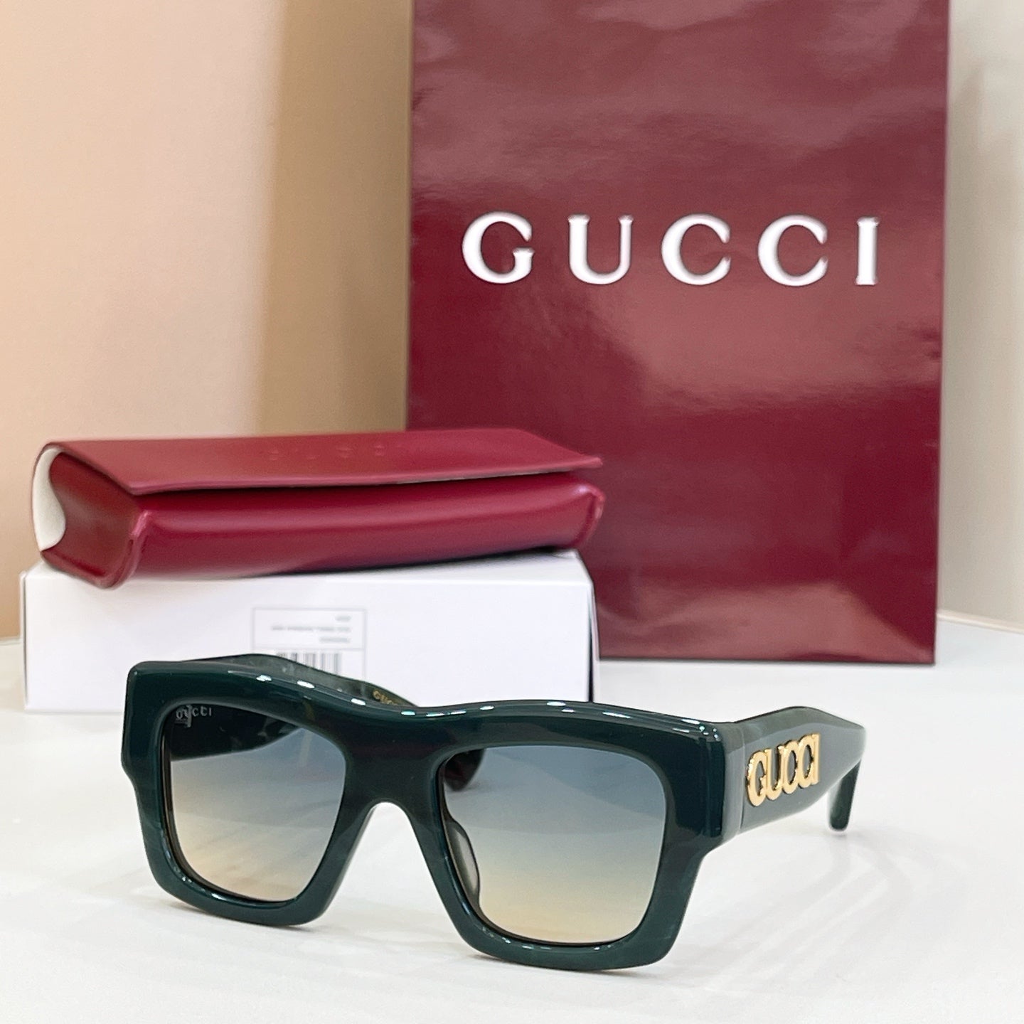 Gucci glasses with dark green square frames and tinted lenses, gold logo on temple.