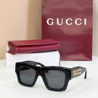 Gucci glasses with black square frames and dark lenses, gold 'gucci' on temple.