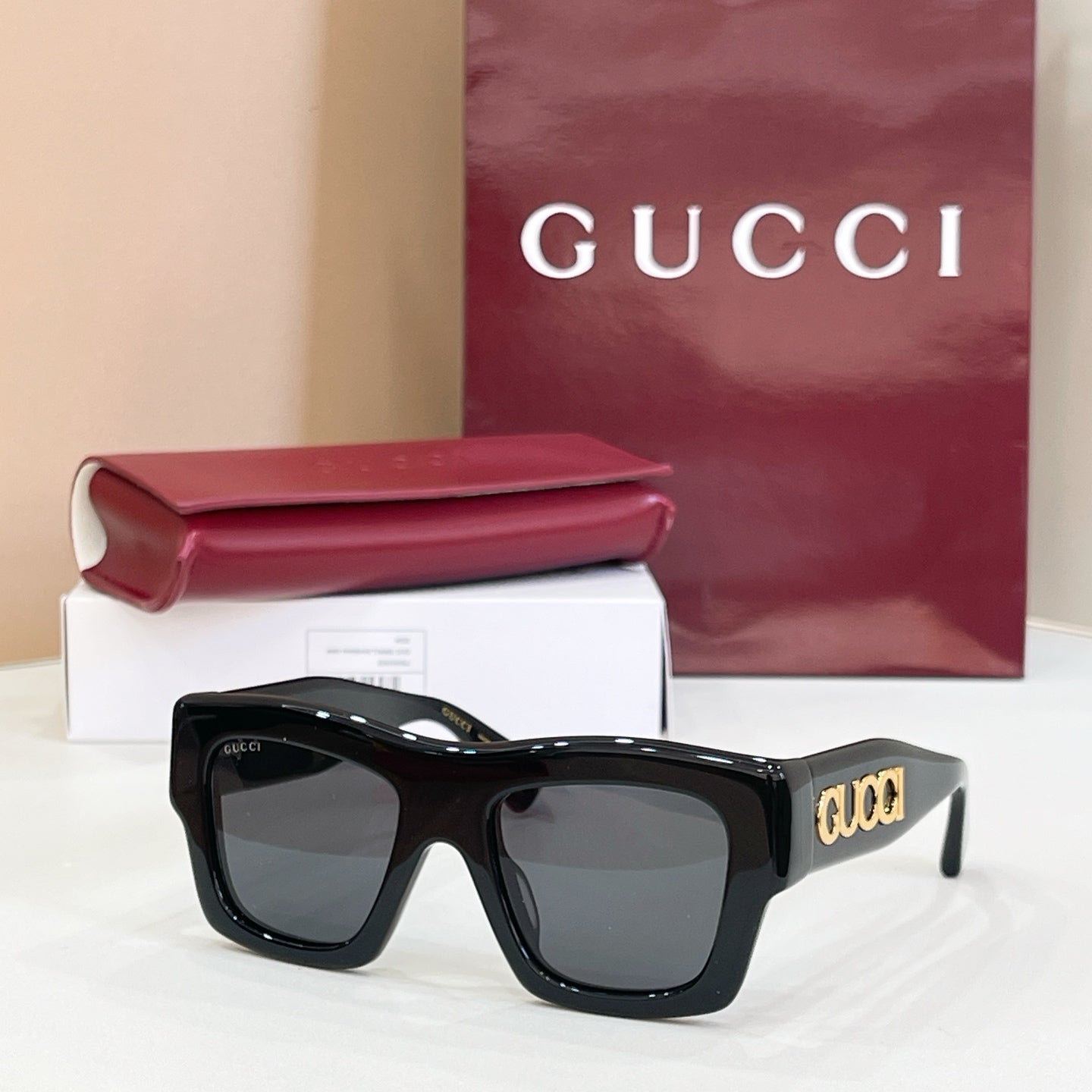 Gucci glasses with black square frames and dark lenses, gold 'gucci' on temple.
