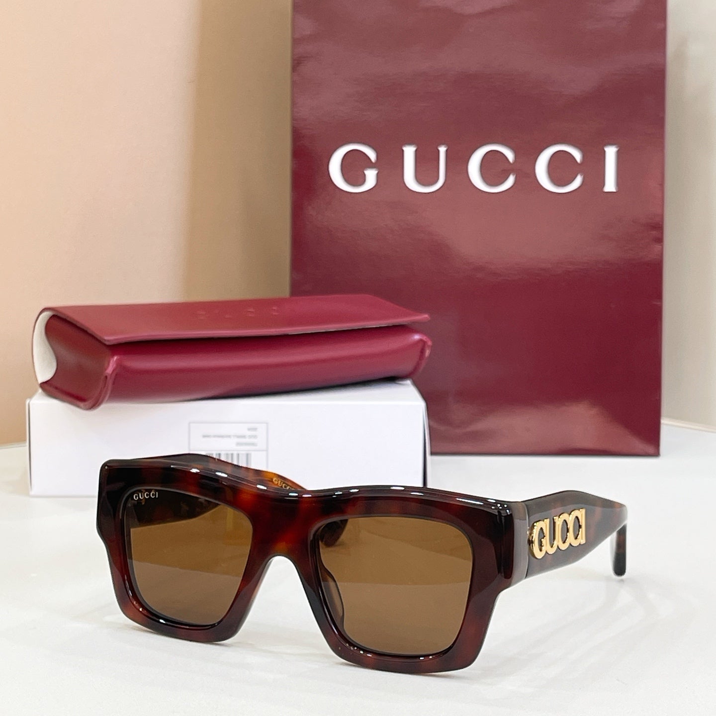 Gucci glasses with tortoiseshell square frames and brown tinted lenses, gold logo on temple.