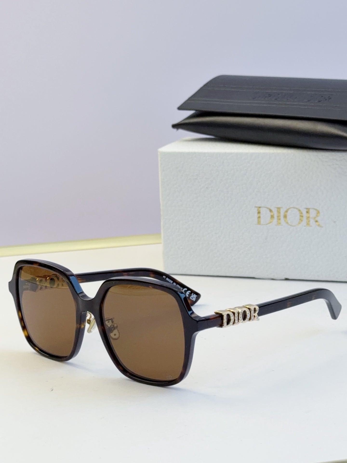 Dior brown-tinted sunglasses with black frame and gold “Dior” temple logo