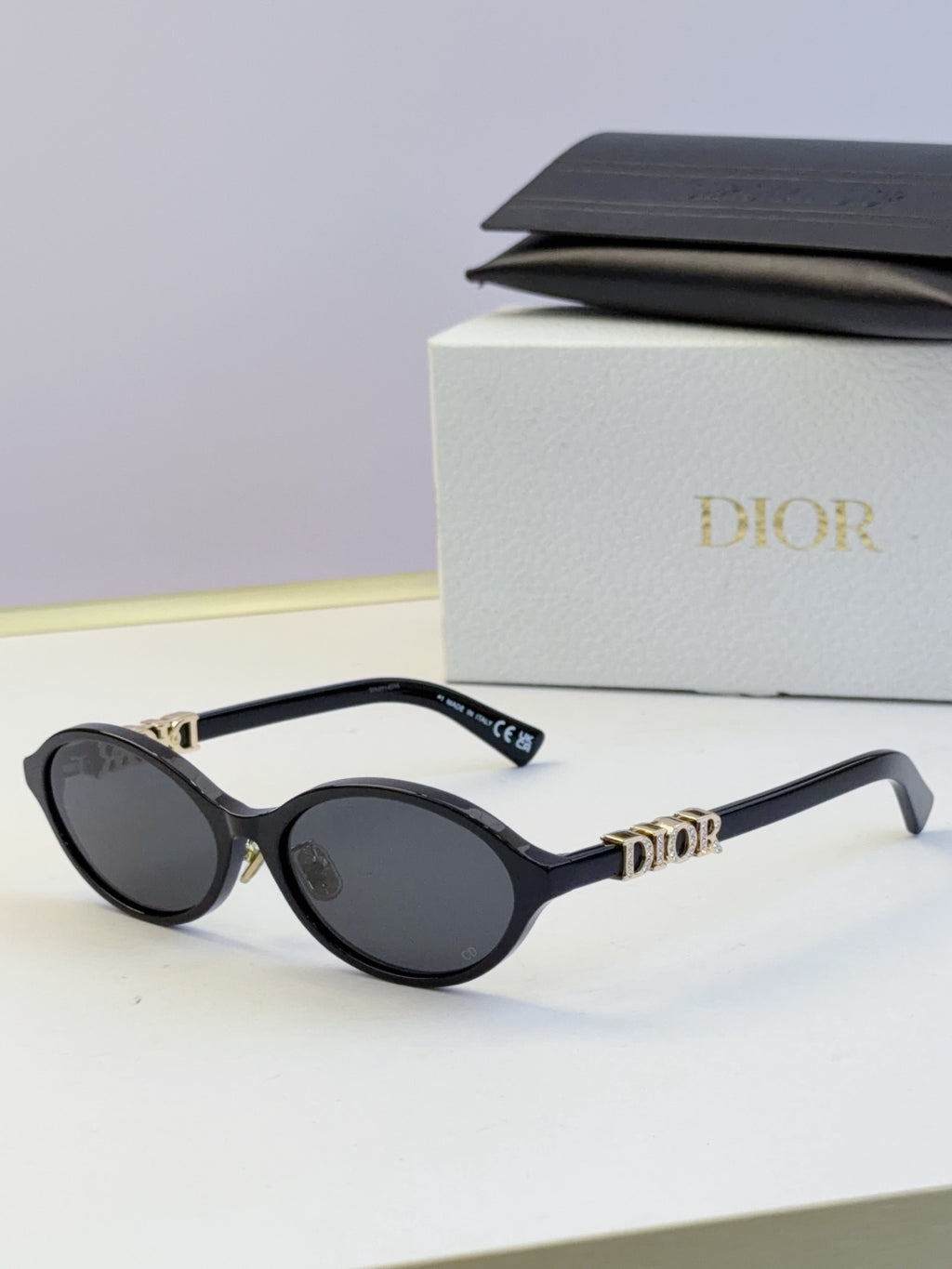Dior round eyeglasses with black frame, dark lenses, and gold logo temples