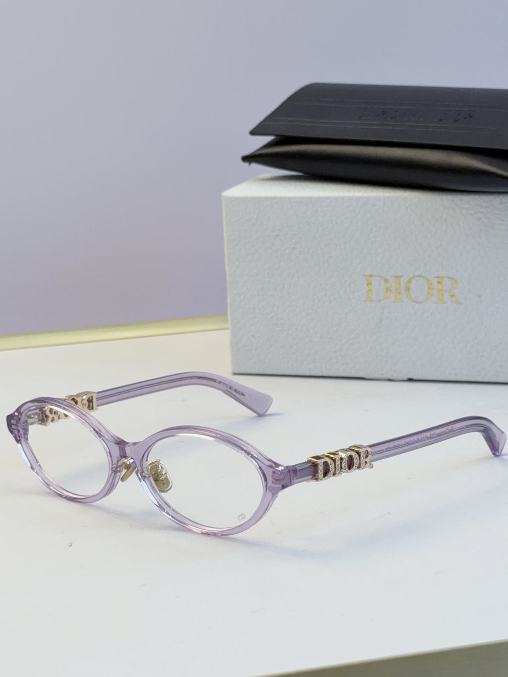 Dior round eyeglasses with light purple frame, light lenses, and gold logo temples