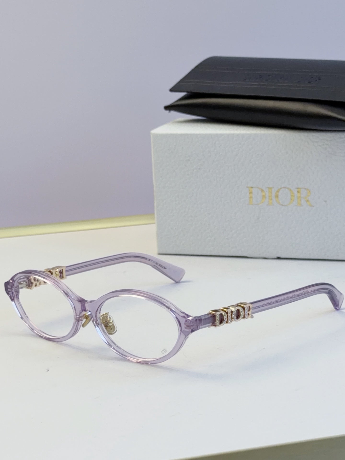 Dior round eyeglasses with light purple frame, light lenses, and gold logo temples