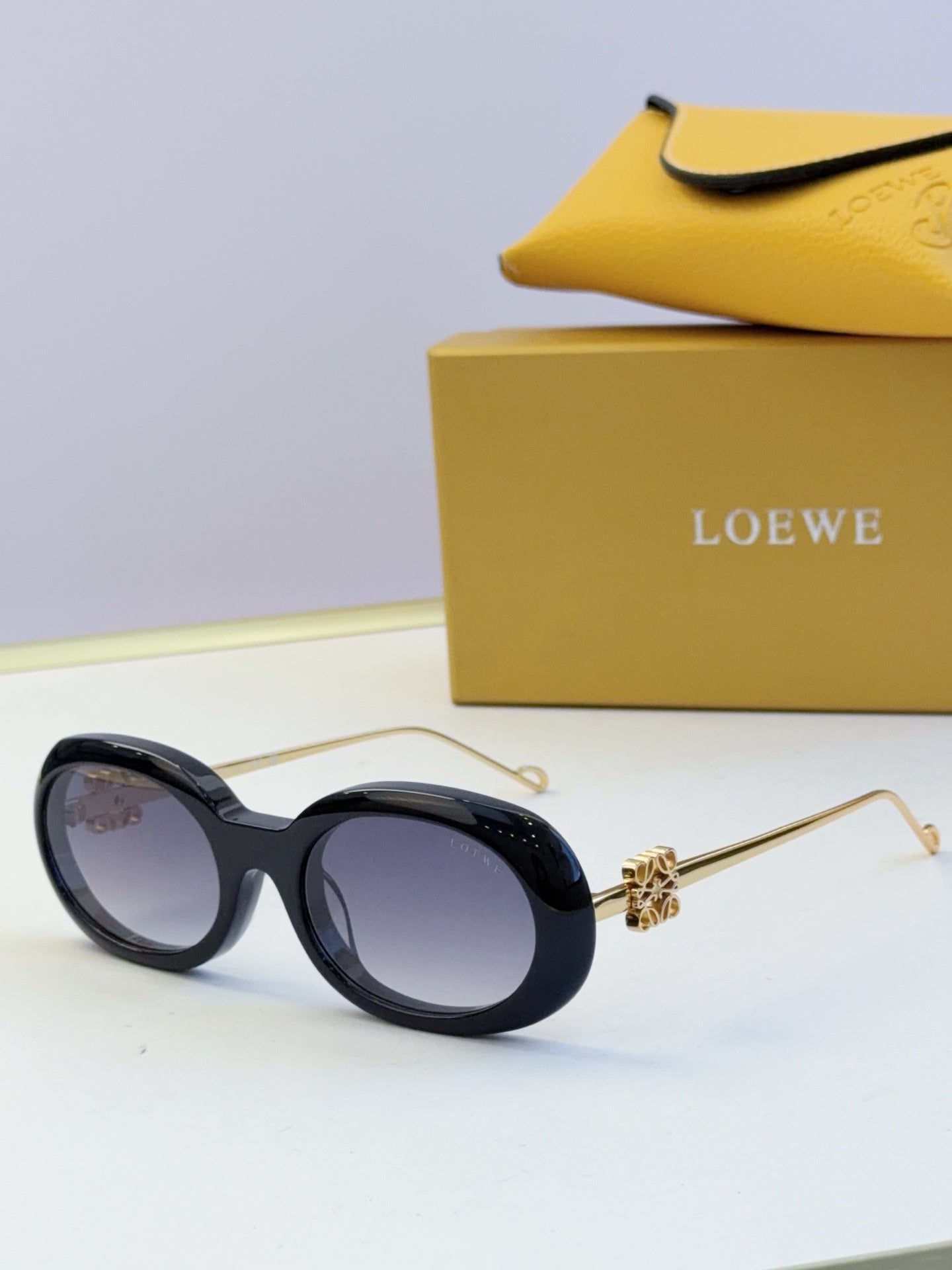 Black oval sunglasses with gold-tone hinges and dark tinted lenses