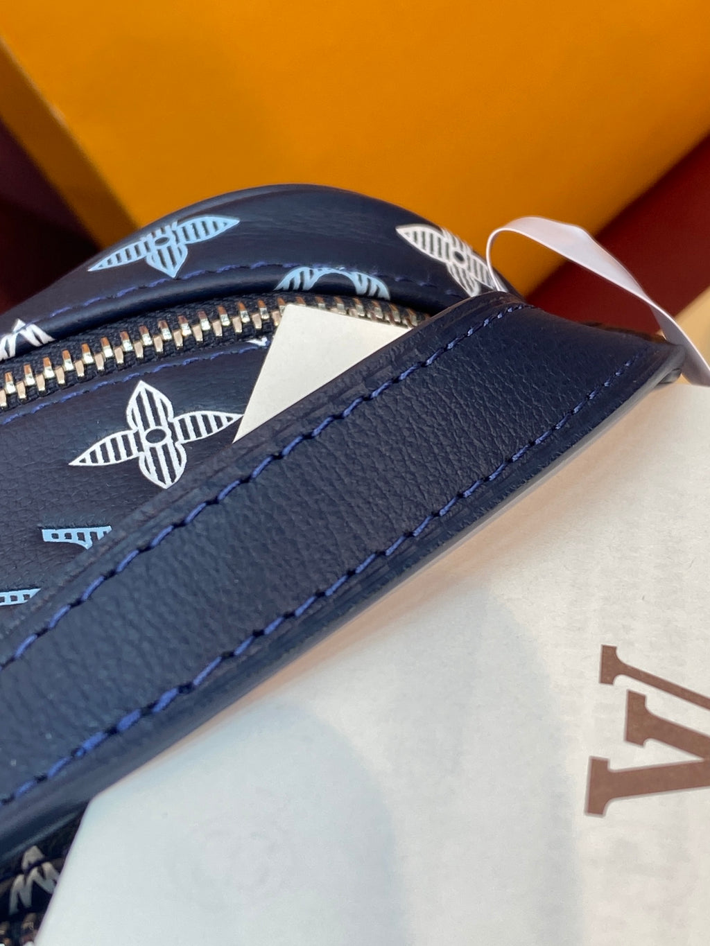 Louis Vuitton navy leather bag with white logo pattern and zipper edge detail