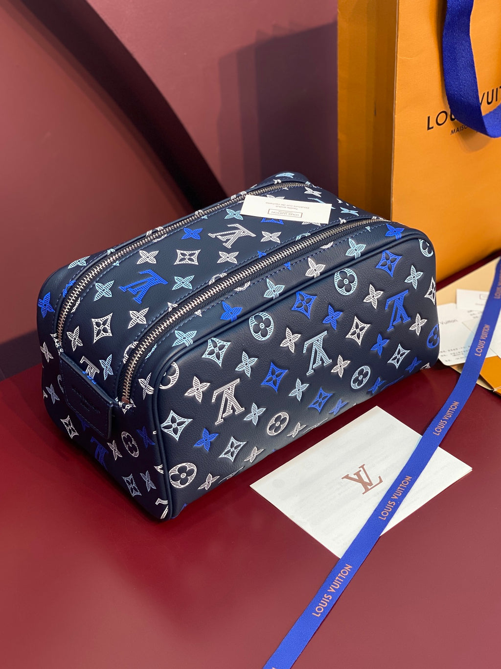 Louis Vuitton bag in black with blue monogram pattern, curved top zip, crossbody strap.