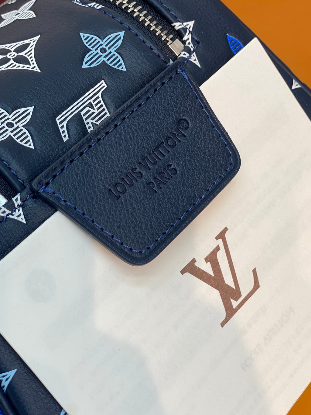 Louis Vuitton label on dark blue leather tab, blue monogram fabric and care tag.