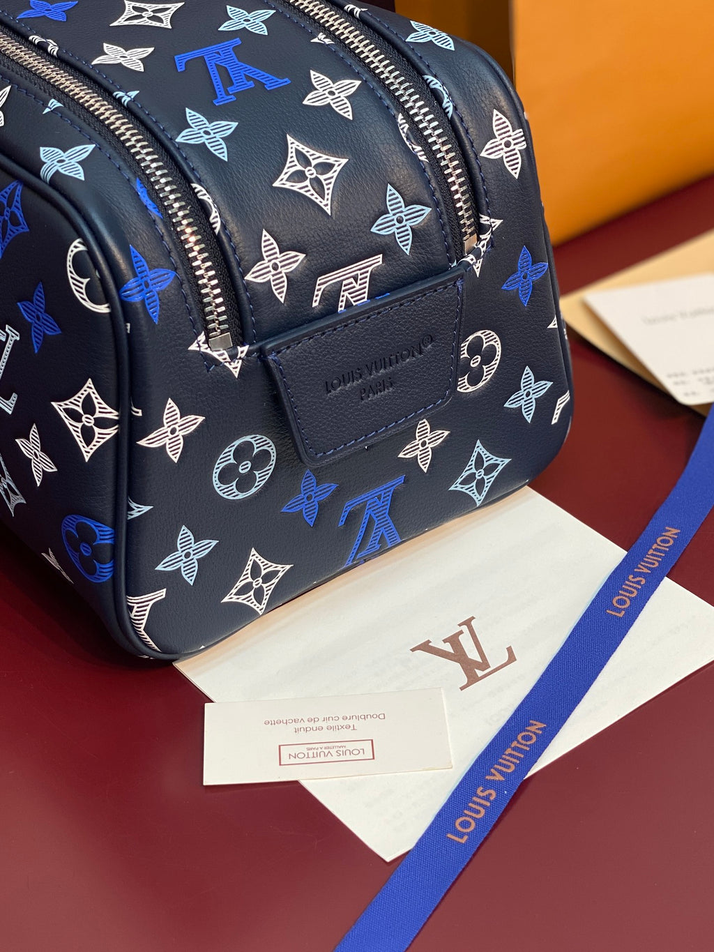 Louis Vuitton bag close-up: black fabric with blue monogram, front patch pocket, zipper.