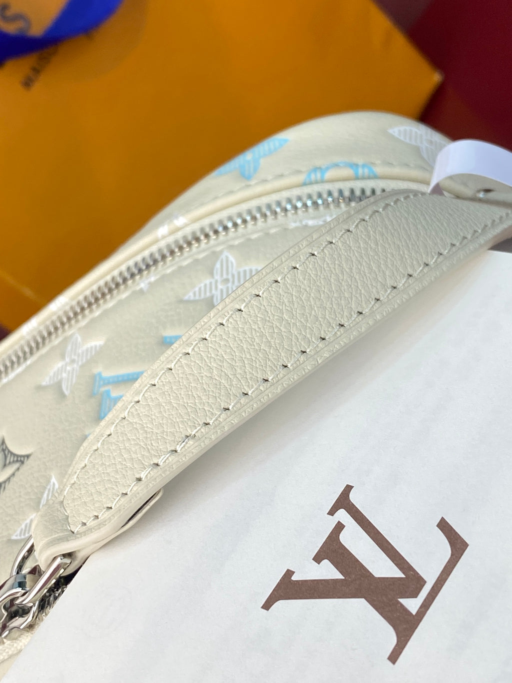 Louis Vuitton bag with cream leather zipper, strap, and LV logo detail