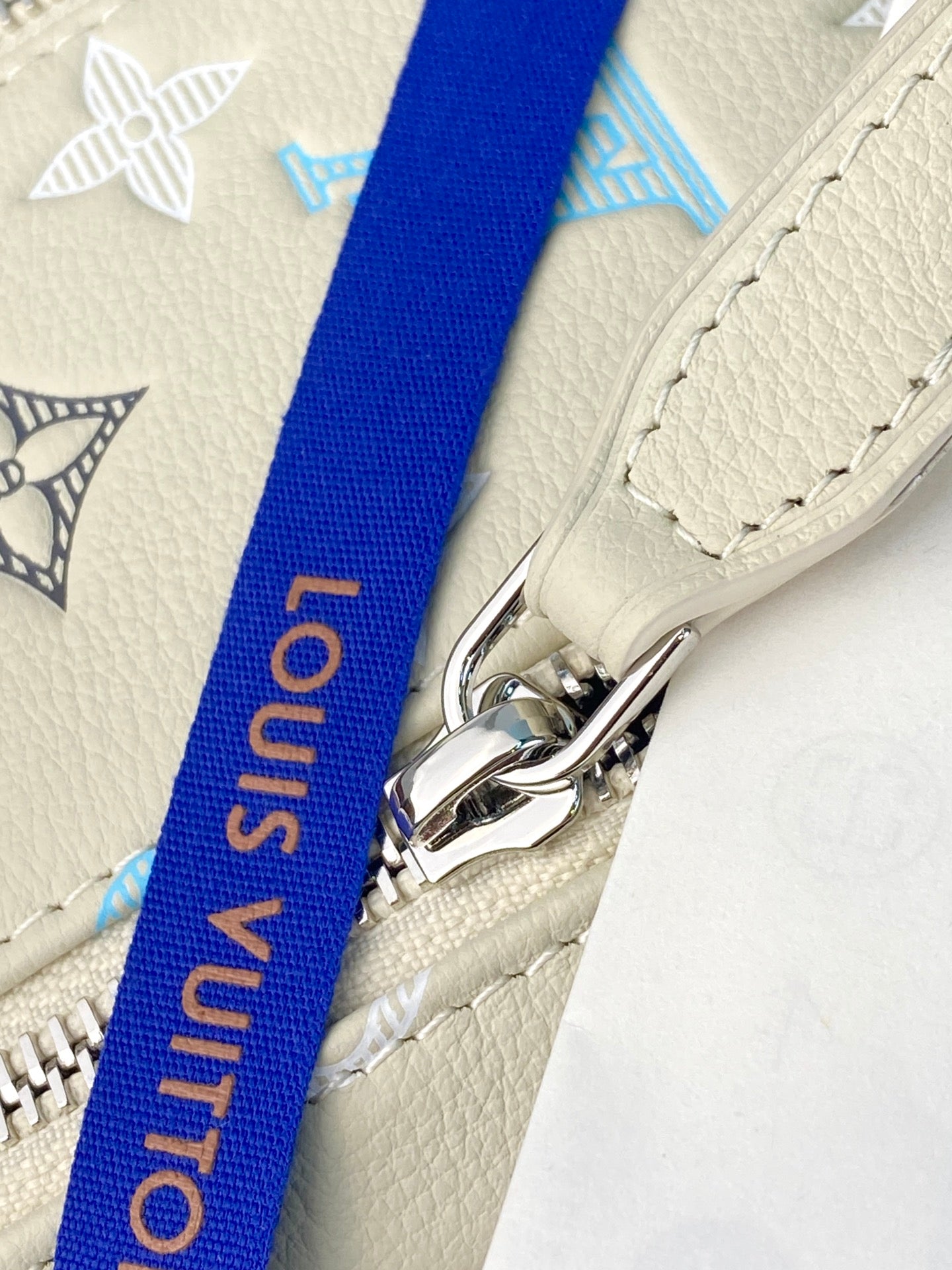 Louis Vuitton bag with cream leather strap, blue webbing, and metal clasp