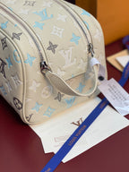 Louis Vuitton monogram bag with light beige strap, blue motifs, and silver zipper pull