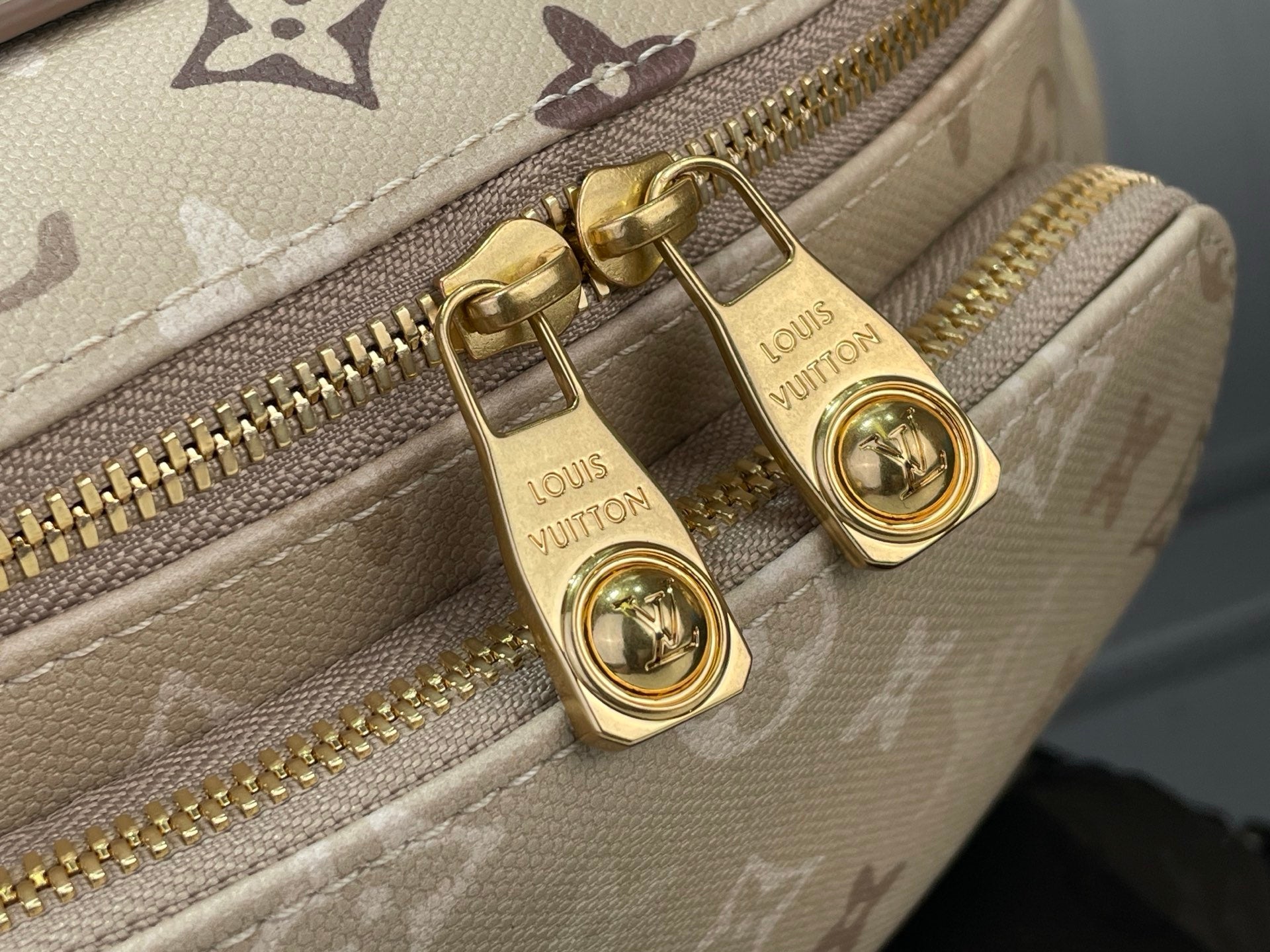 Louis Vuitton monogram belt bag close-up with gold zippers and logo pull tabs