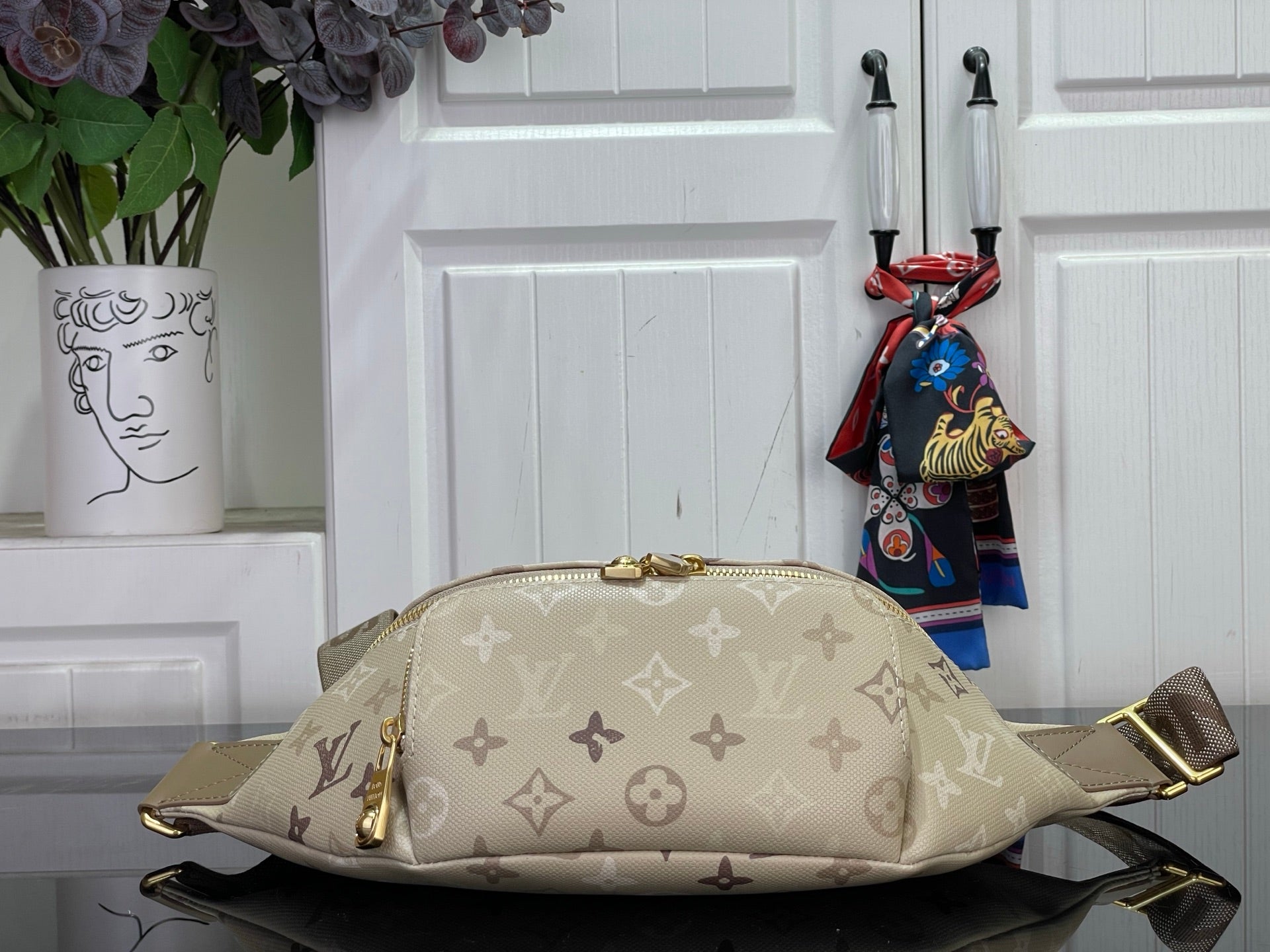 Beige Louis Vuitton monogram waist bag with top zipper, gold clasps, and side straps