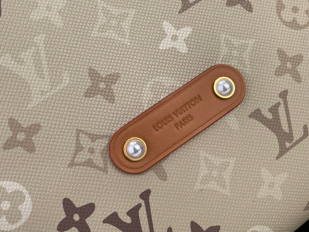 Tan leather tab with gold-tone snaps on beige monogram bag