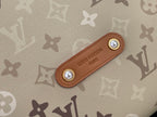 Tan leather tab with gold-tone snaps on beige monogram bag