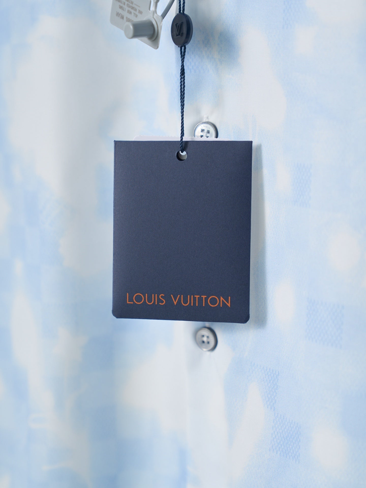 Louis Vuitton black hang tag on light blue short-sleeve shirt