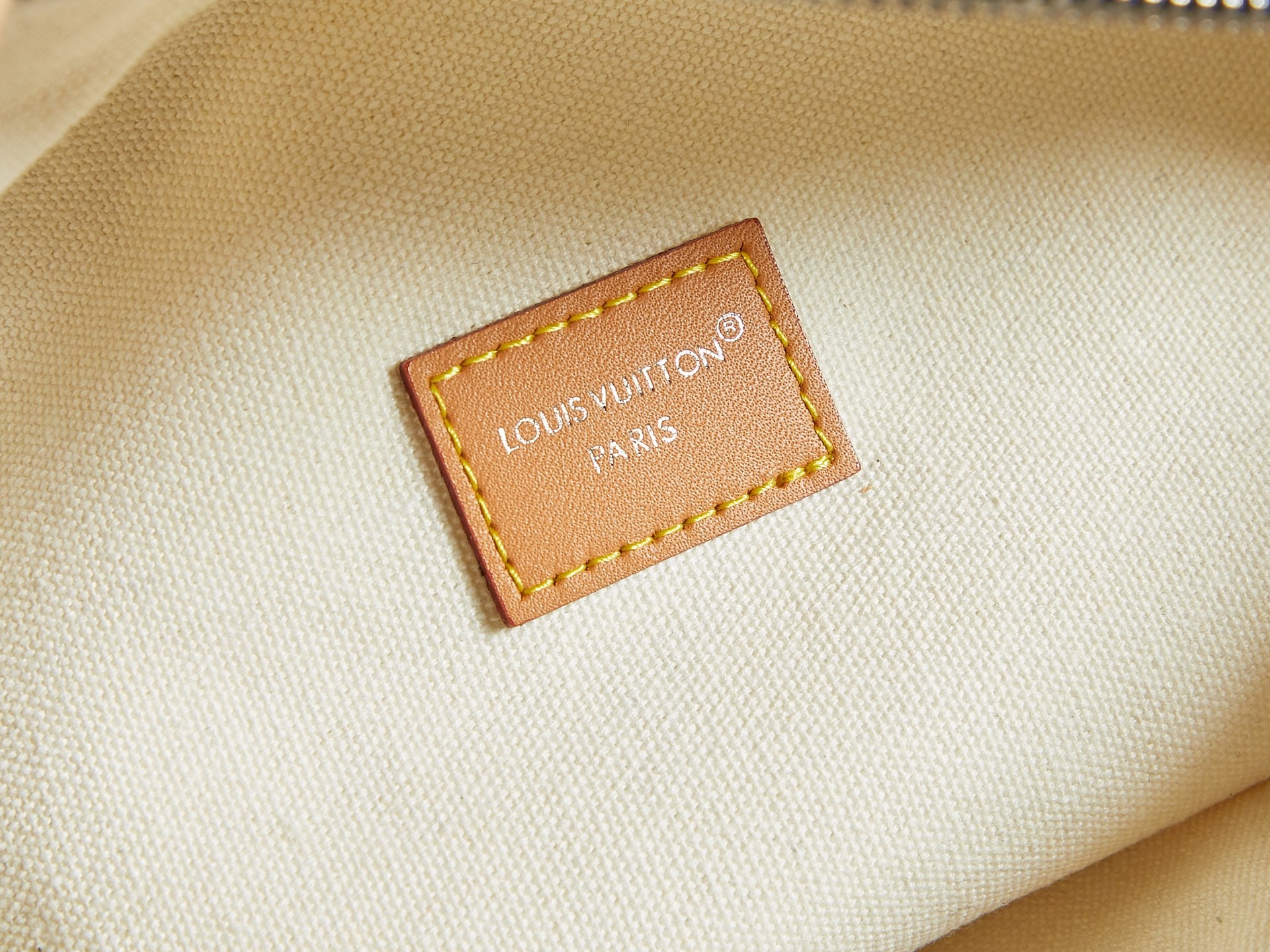 Louis Vuitton interior label on cream fabric lining with tan border stitching