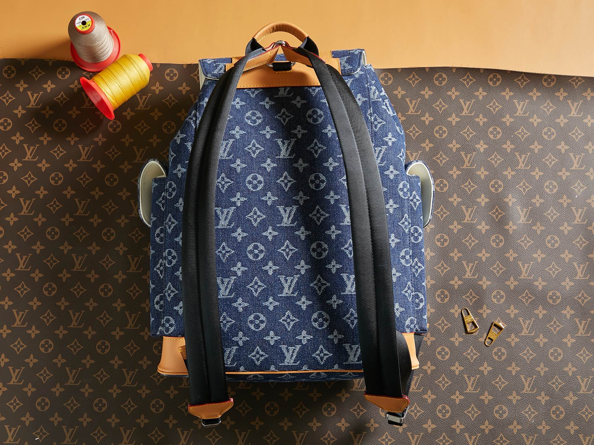 Blue monogram duffel bag with black side straps and tan leather base