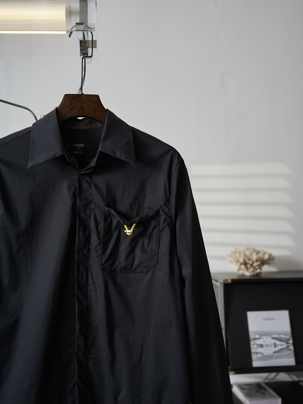 Fendi dark long jacket close-up of chest pocket and small yellow logo detail