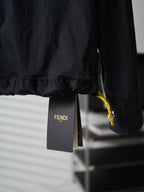 Fendi dark long jacket hem close-up with yellow interior trim and hanging tag