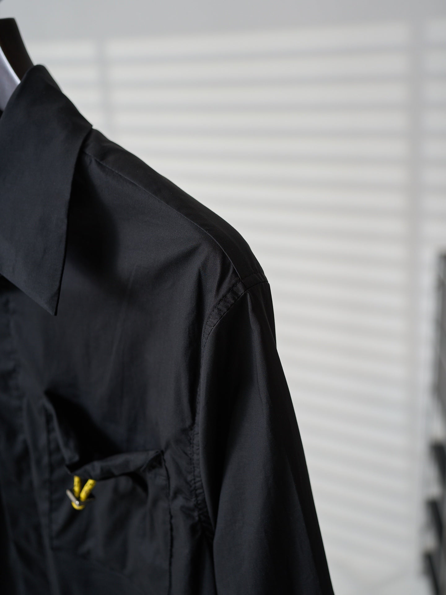 Fendi dark long jacket side view with shoulder seam and small yellow logo
