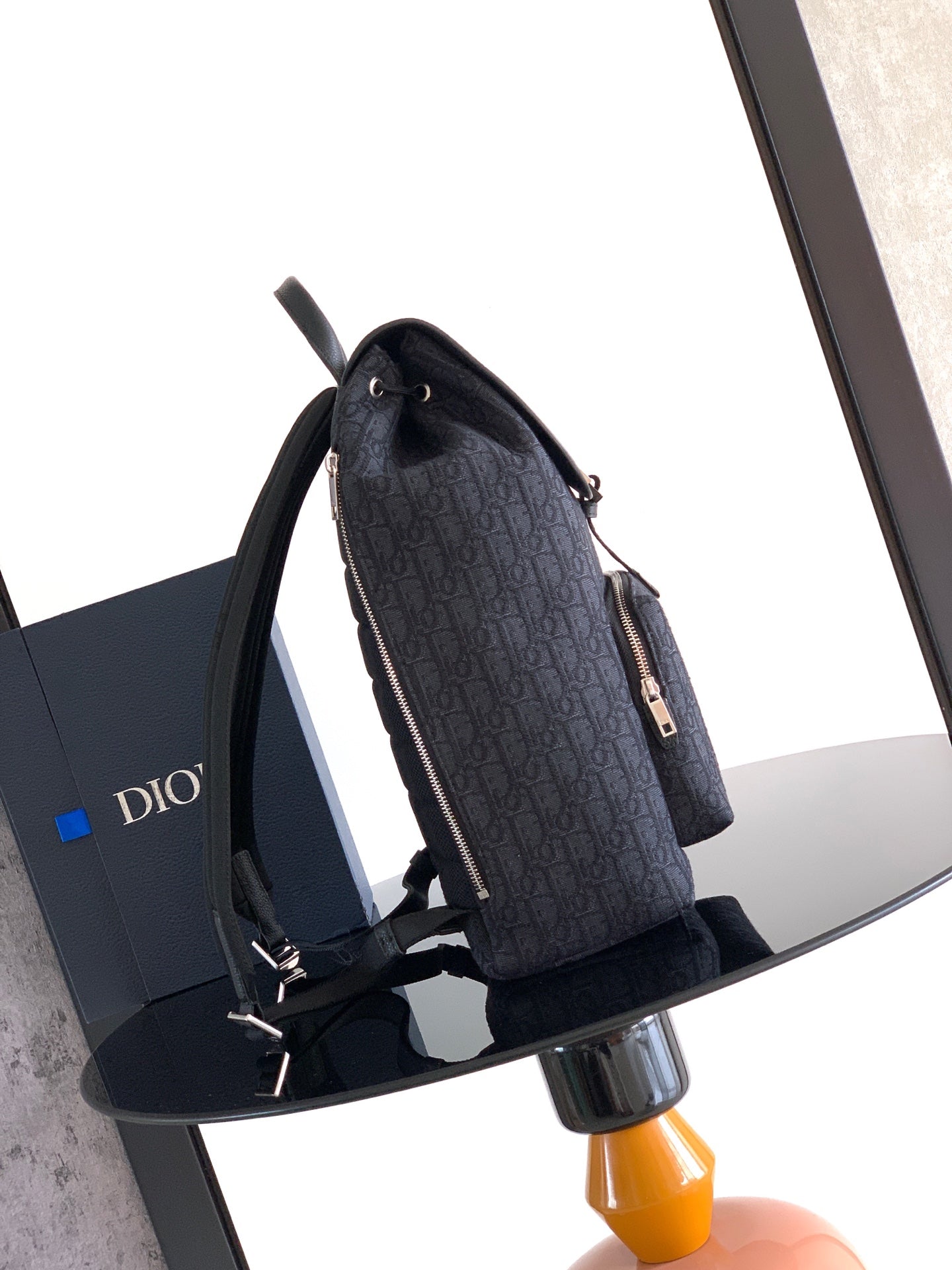 Navy Dior backpack side view with shoulder straps and zipper pocket