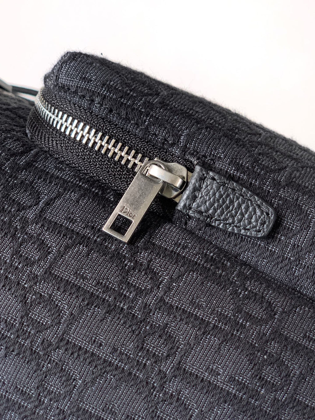 Dark monogram bag with silver zipper pull and leather tab