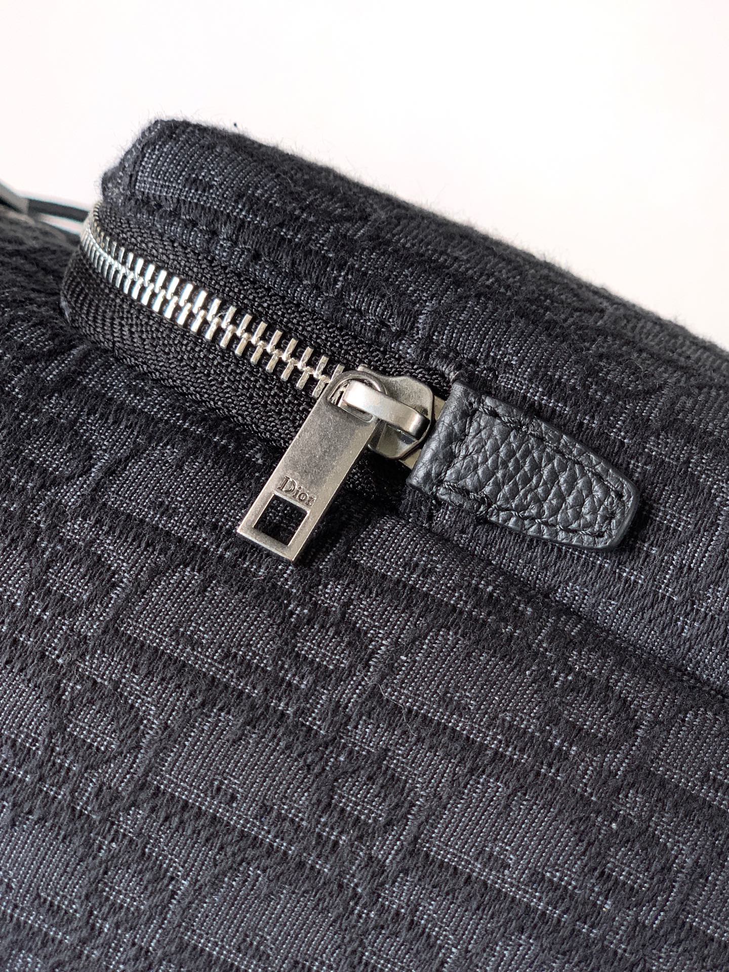 Dark monogram bag with silver zipper pull and leather tab
