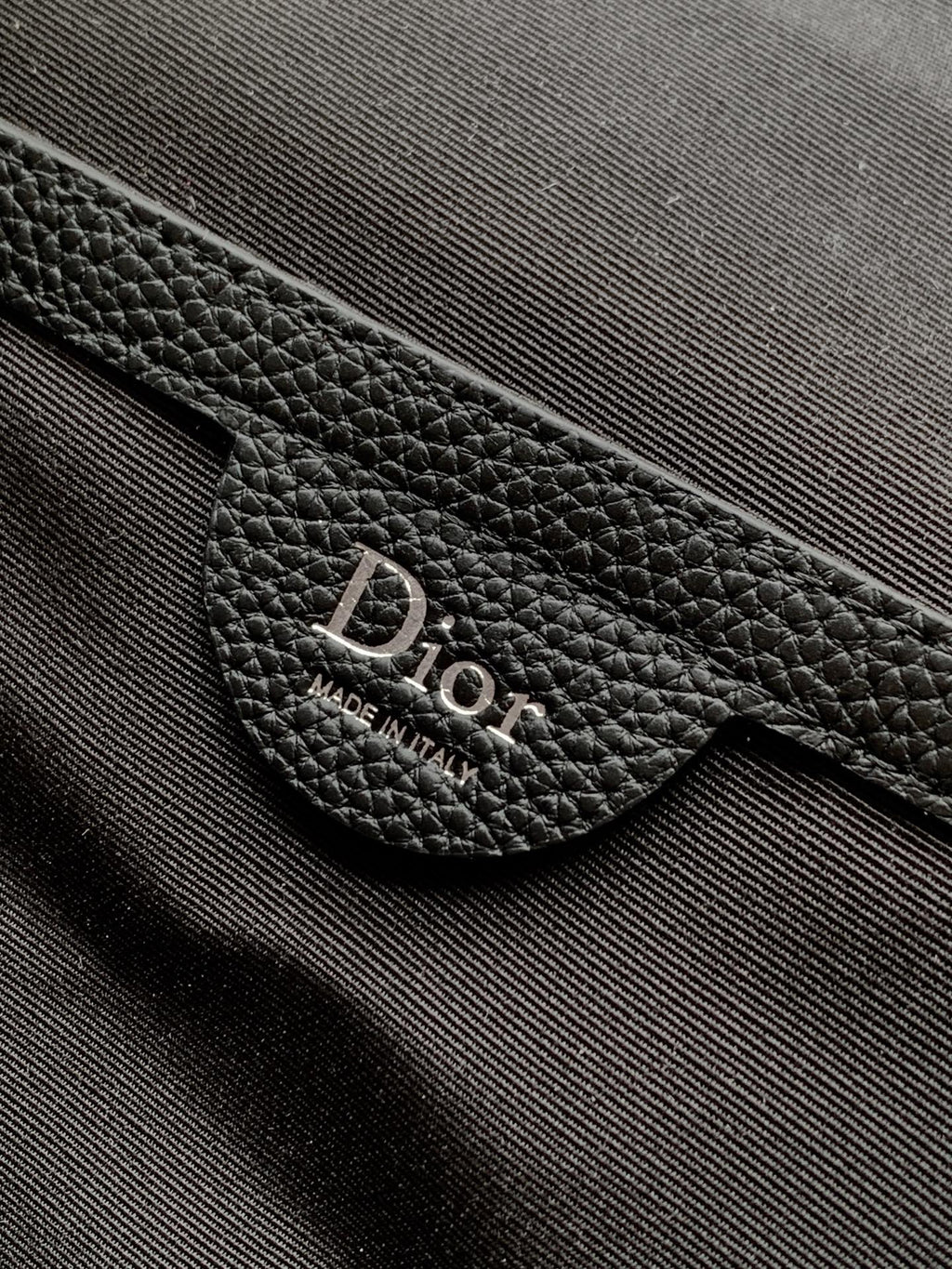 Black leather Dior label reading Made in Italy on strap tab