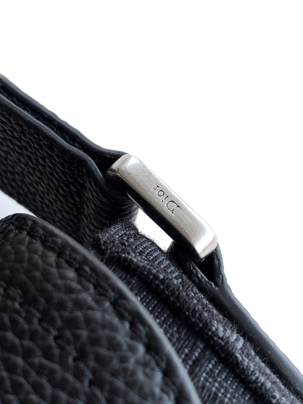 Dior bag close-up: metal clasp on textured leather strap