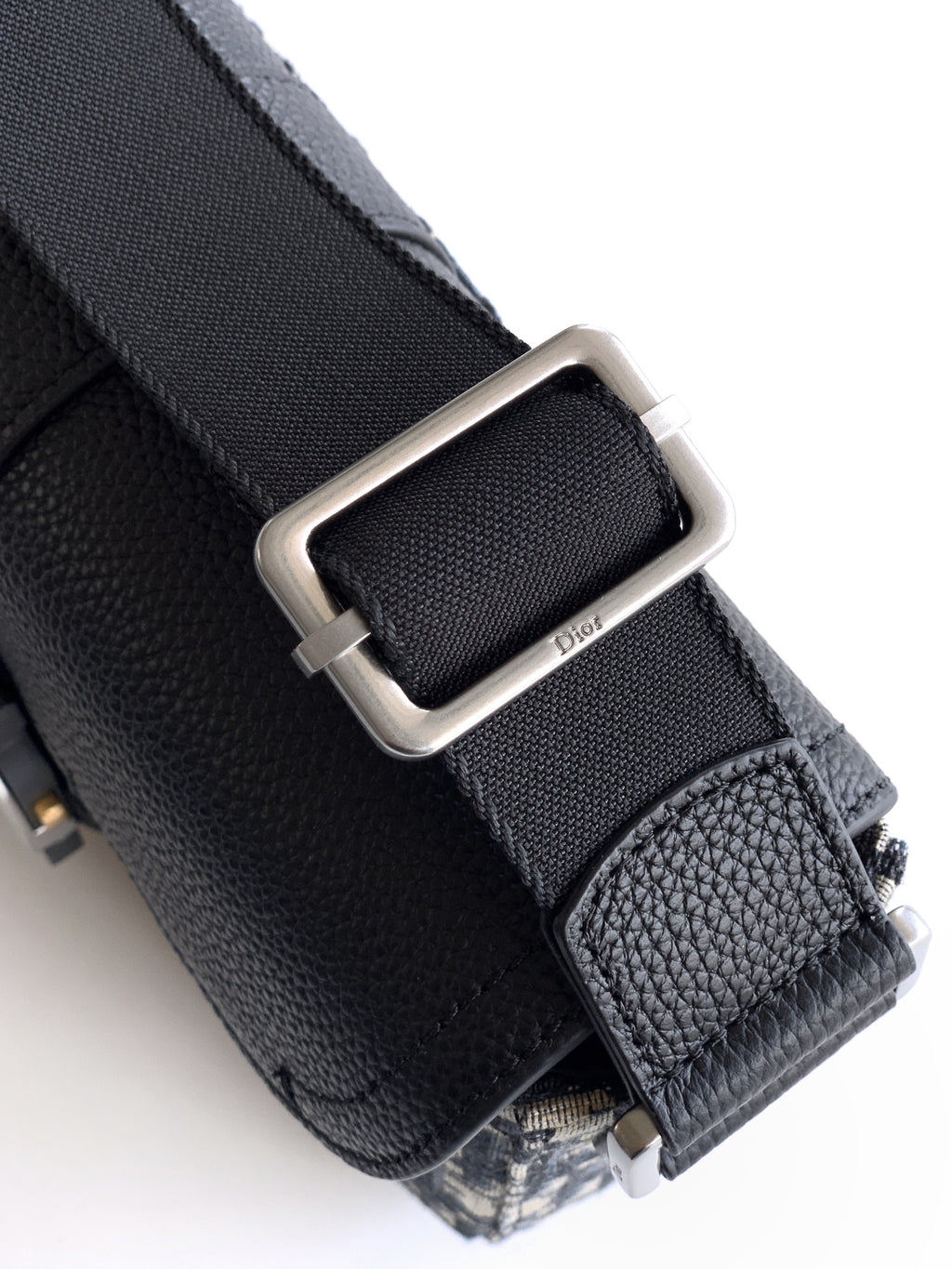 Dior bag hardware close-up with black leather strap and silver buckle