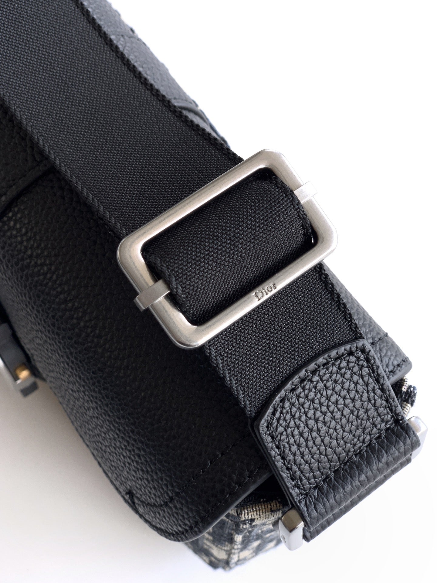 Dior bag hardware close-up with black leather strap and silver buckle