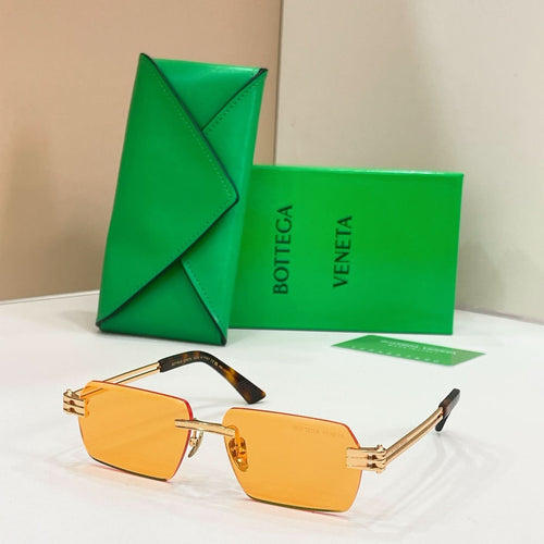 Bottega Veneta sunglasses with amber-orange lenses, gold-tone frames, and tortoise-detail temples