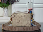 Beige monogram crossbody bag with wide patterned strap and gold-tone hardware.