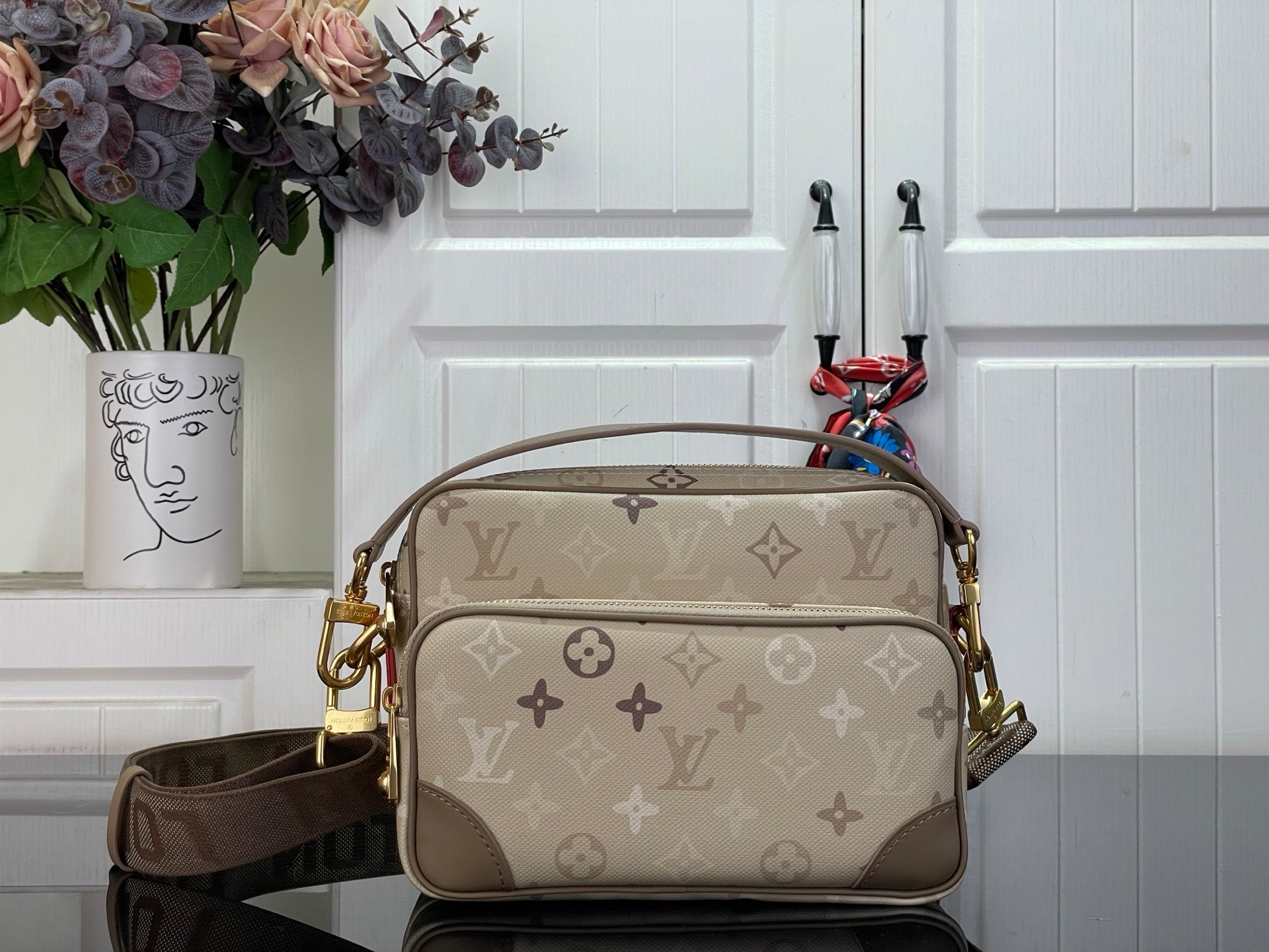 Beige monogram crossbody bag with top handle and shoulder strap, gold-tone hardware.