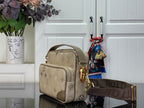 Beige monogram crossbody bag with stacked front pocket and top handle, gold hardware.