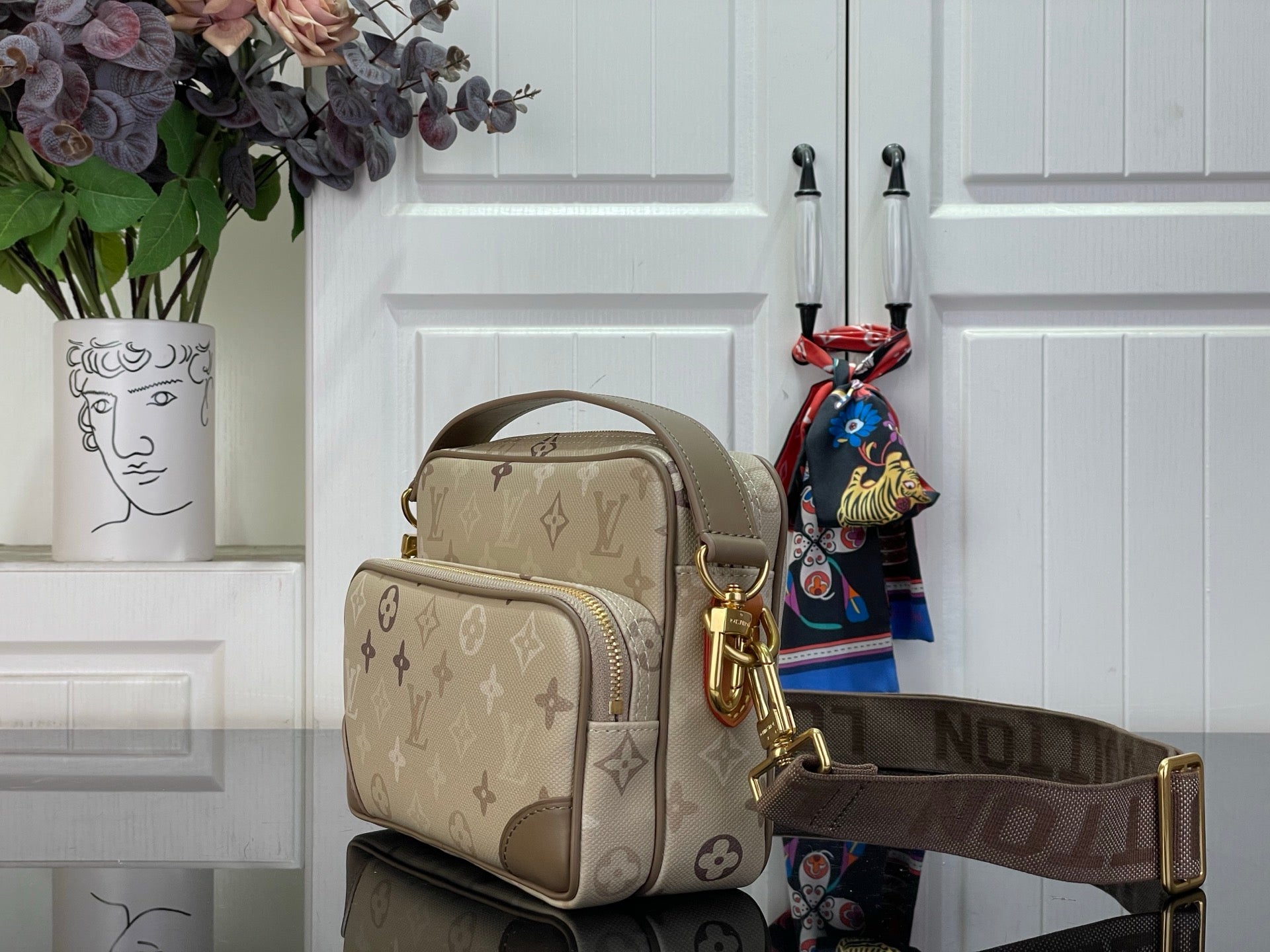 Beige monogram crossbody bag with stacked front pocket and top handle, gold hardware.
