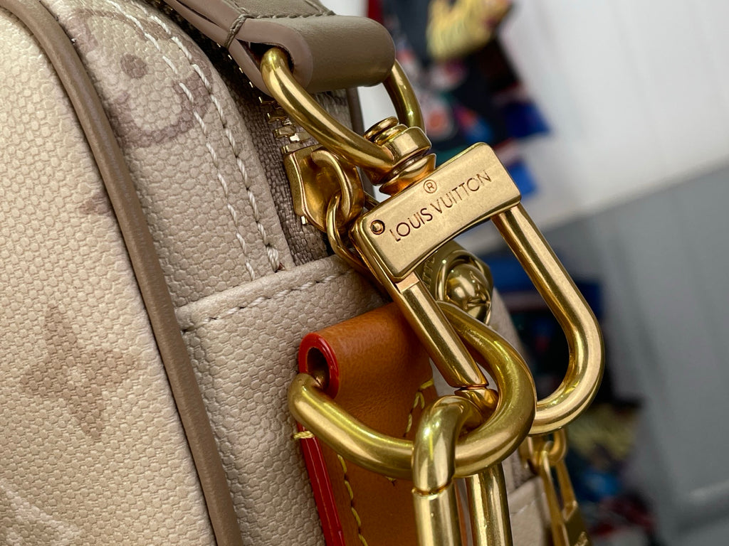 Beige monogram bag with gold-tone hook clasp and brown leather strap detail.
