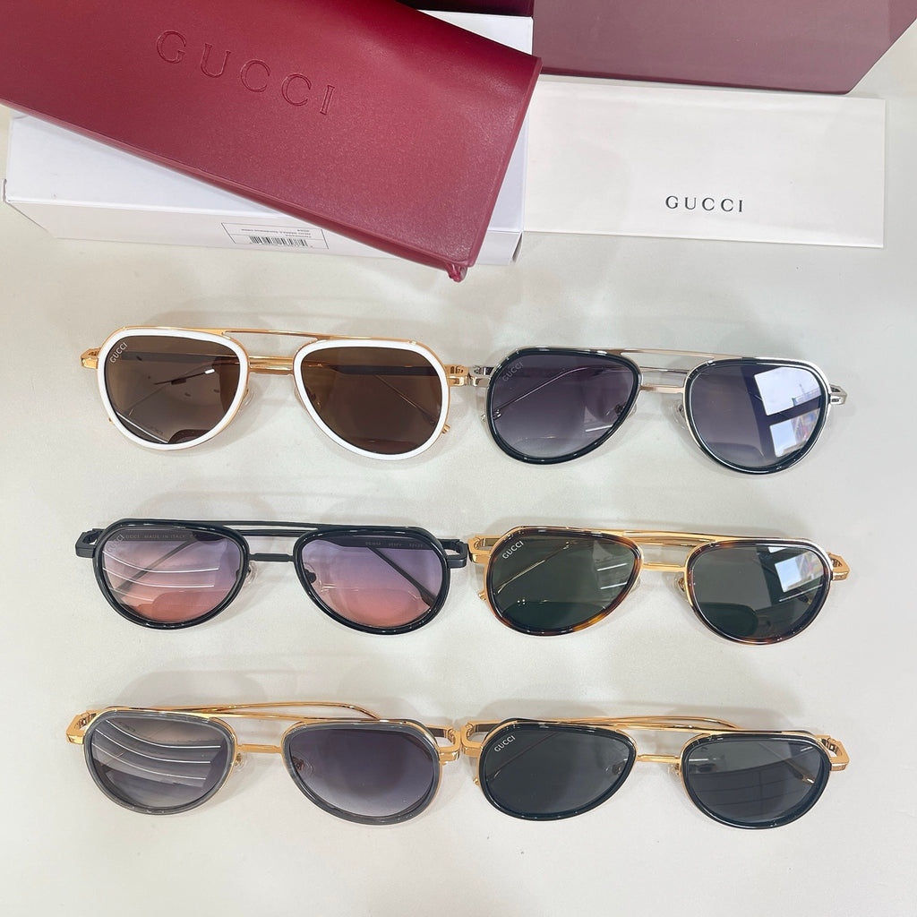 Multiple Gucci sunglasses laid out, mixed frames including white/gold, tortoiseshell, and dark