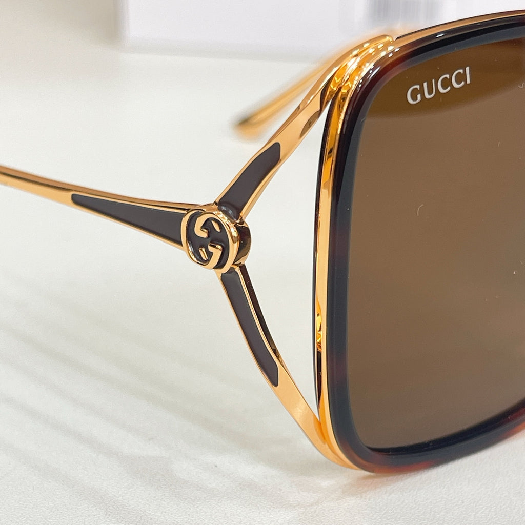 Gucci sunglasses close-up, gold-tone frame with brown lenses