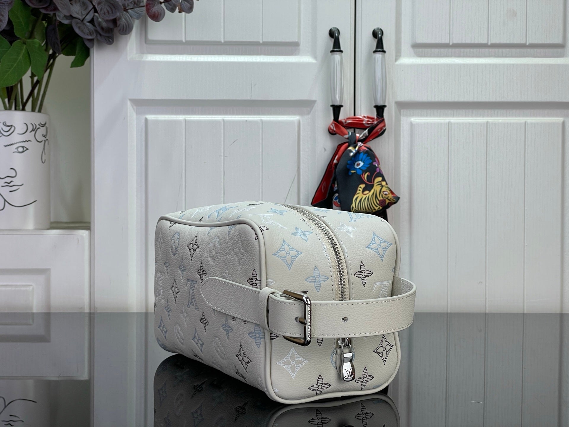 Cream monogram shoulder bag with blue icons, front strap, and silver buckle