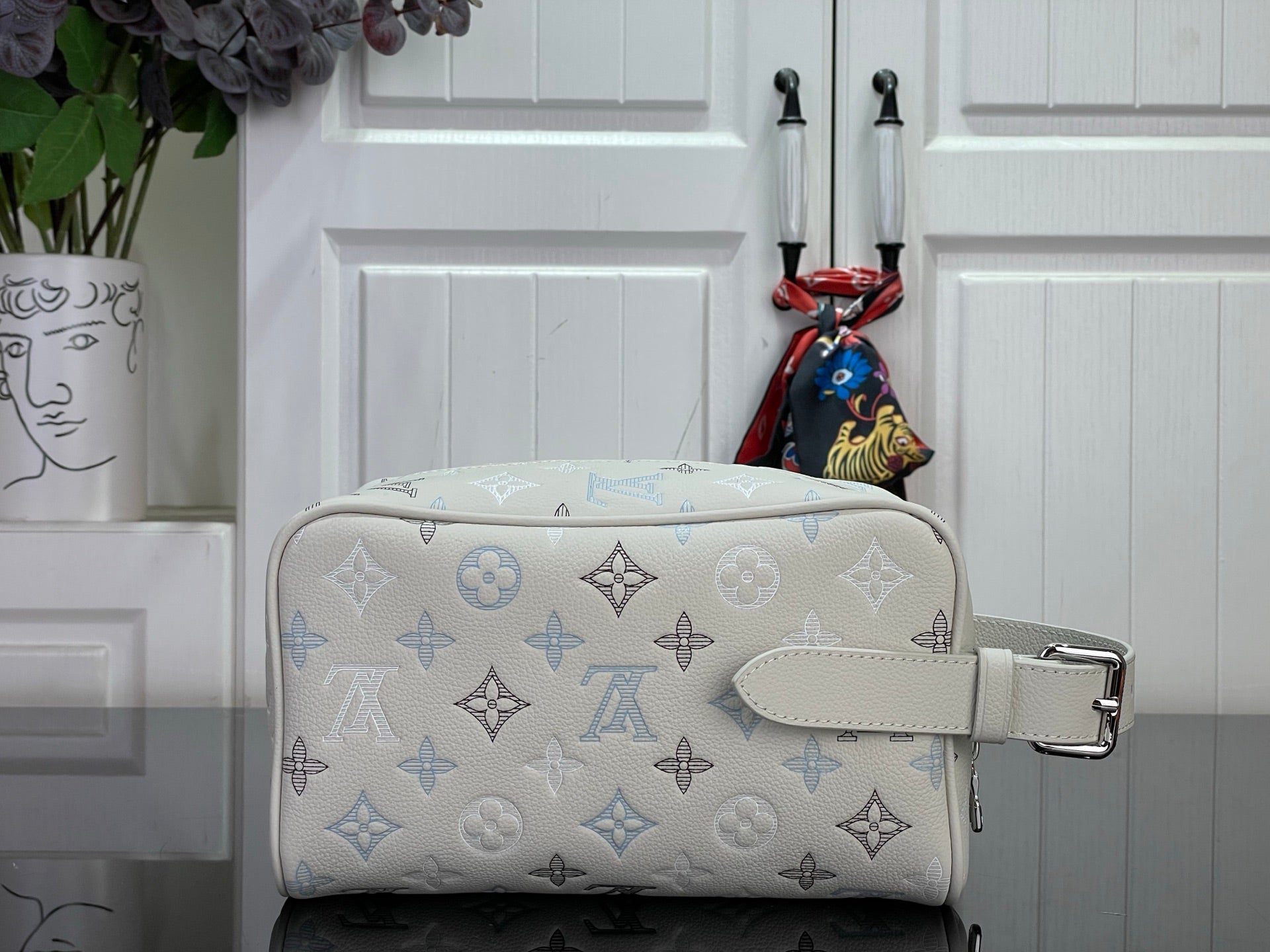 Cream monogram crossbody bag with blue print, adjustable strap, and silver buckle