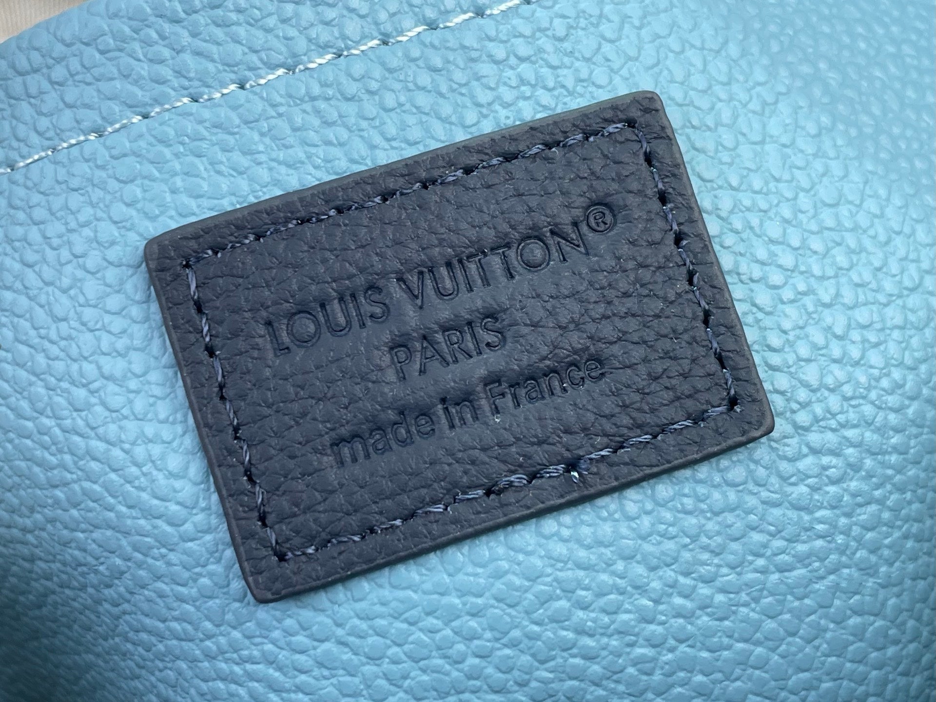 Louis Vuitton bag close-up of navy leather label reading Louis Vuitton Paris and Made in France