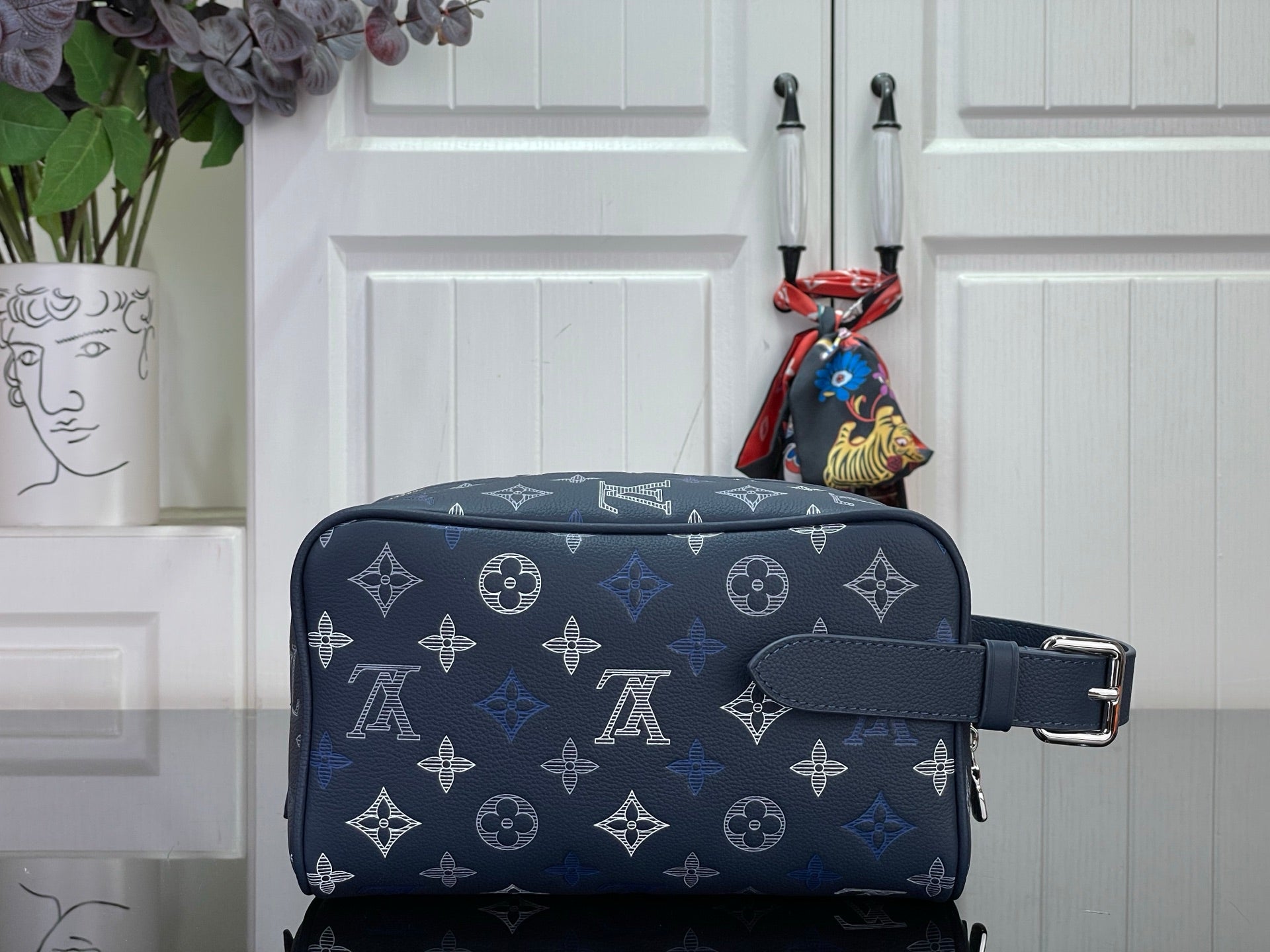 Louis Vuitton bag in dark navy with monogram, front strap, and metal buckle